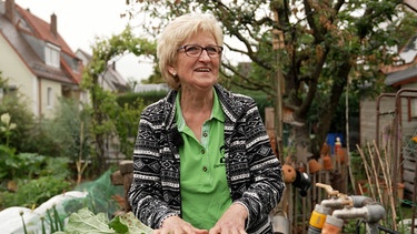 Eine blonde ältere Frau steht in ihrem Garten: Die "Garten-Moni". | Bild: BR24/Ursula Schmidt