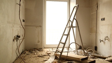 Eine Klappleiter steht in einer zerstörten Wohnung | Bild: BR