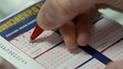 Person füllt Lottoschein aus | Bild: BR