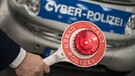 Hand hält Polizeikelle vor Auto mit Aufschrift "Cyber-Polizei" | Bild: picture-alliance/dpa