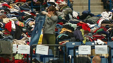 Eine Frau sortiert Kleidungsstücke | Bild: BR
