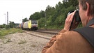Ein Mann fotografiert einen Zug | Bild: BR