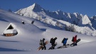 Vier Snowboarder beim Anstieg in verschneiter Berglandschaft | Bild: BR