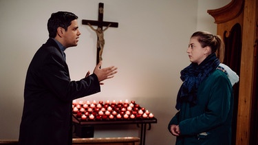 Dahoam is Dahoam: Sarah (Sophie Reiml) hat durch Jennys Tod den Glauben an Gott verloren und lässt sich auch von Pfarrer Burman (Daniel Popat) nicht umstimmen. | Bild: Rubberball