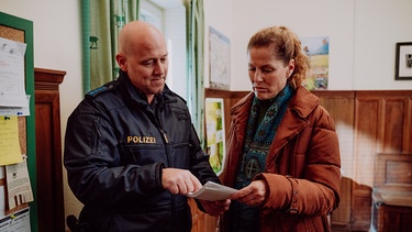 Dahoam is Dahoam: Polizist Haas (Michael Dietmayr, KLD) macht Annalena (Heidrun Gärtner) darauf aufmerksam, dass Betrugsdelikte im digitalen Bereich auf dem Vormarsch sind. | Bild: BR/Nadya Jakobs