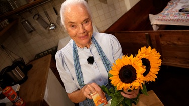 Dahoam is Dahoam: Uri (Ursula Erber) mit Sonnenblumen und einem Päckchen Backpulver. | Bild: BR