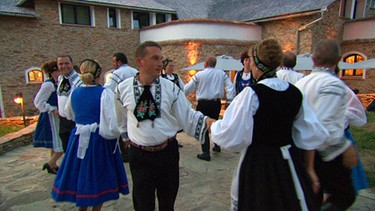 Frauen und Männer tanzen in Tracht. | Bild: BR