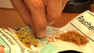 Eine linke Hand in Großaufnahme legt Cannabis und Tabak in ein Zigaretten-Papier | Bild: BR