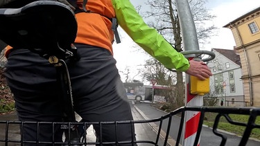 Fahrradfahrer, der den Ampeldrückknopf drückt in Nahaufnahme. | Bild: BR