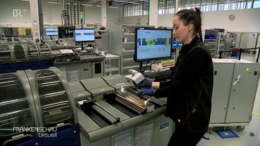 Eine Mitarbeiterin des Chip-Karten-Herstellers legt Karten-Rohlinge in eine Maschine ein. | Bild: BR