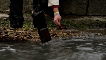 Ein Mann wäscht seinen Geldbeutel im Fluss. | Bild: BR