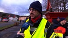 Ein Feuerwehrmann wird zur aktuellen Lage in Gräfendorf interviewt. | Bild: BR