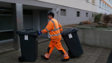 Ein Müllmann bewegt zwei gechippte Mülltonnen. | Bild: BR