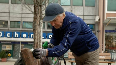 Der Rentner Walter Siebert reinigt eine Parkbank. | Bild: BR