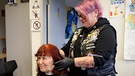 Eine Frau von den Barberangels beim Haare schneiden in der Bahnhosmission Aschaffenburg. | Bild: BR