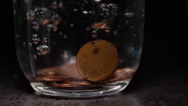 Kupfergeld fällt in Wasserglas. | Bild: BR