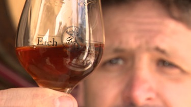 Georg Kugler hält einen Whisky-Schwenker mit seinem Whiksy "Torf vom Dorf". | Bild: BR