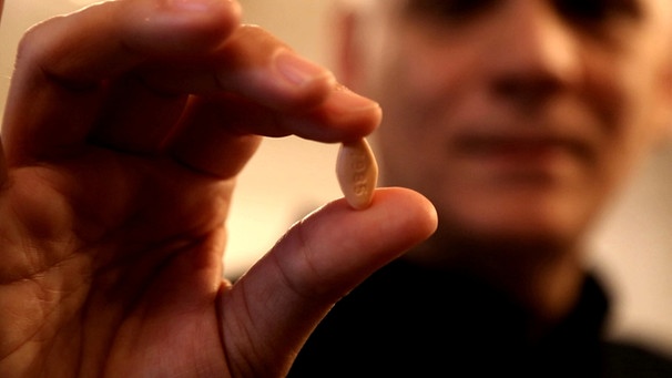 Tablette gegen Hepatitis C, gehalten zwei Fingern | Bild: Florian Heinhold, BR