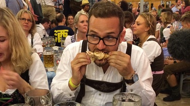Rainer Maria Jilg isst ein Hendl beim Experiment "24 Stunden auf der Wiesn mit 50 Euro" | Bild: BR