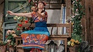 Der Komödienstadel - Ein Garten voll Schlawiner: Luana (Corinna Binzer) meditiert auf dem "Kraftbankerl" vor Franziskas Haus. | Bild: BR/Julia Müller
