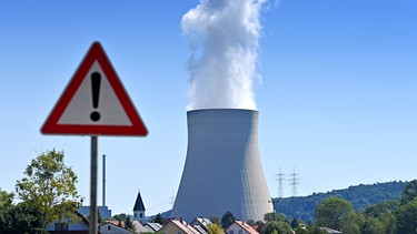 Kühlturm eines Kernkraftwerks, im Vordergrund ein Verkehrsschild mit Ausrufezeichen | Bild: picture alliance / Sven Simon, Frank Hoermann