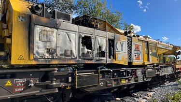 Ein Eisenbahnkran ist auf einem Abstellgleis in Unterföhring in der Nacht vom 27.10. zum 28.10.2023 durch ein Feuer stark beschädigt worden. Laut Polizei ist die Brandursache noch unklar. | Bild: BR/Frank Jordan