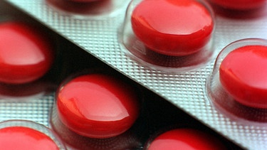 Mit roter Glasur überzogene Tabletten in ihrer Verpackung aus Plastik und Alu-Folie | Bild: picture-alliance / dpa | Frank Kleefeldt