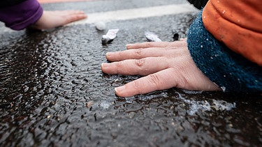 Klimaaktivisten haben ihre Hände auf einer Straße festgeklebt. (Symbolbild) | Bild: picture alliance / Hendrik Schmidt