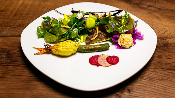 Gefüllte Zucchini- und Malvenblüte auf Blatt-Kräuter-Salat | Bild: BR/megaherz gmbh/Andreas Maluche