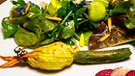 Gefüllte Zucchini- und Malvenblüte auf Blatt-Kräuter-Salat | Bild: BR/megaherz gmbh/Andreas Maluche
