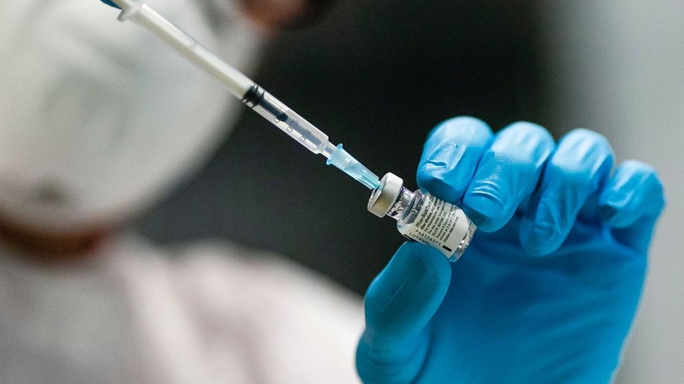 Eine Impfspritze wird von medizinischen Fachpersonal in eine Impfdose gesteckt. | Bild: BR-Bild