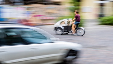 Ein Auto und im Hintergrund ein Lastenrad | Bild: picture alliance/dpa | Christoph Soeder
