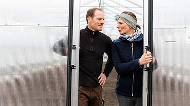 Carolin und Andreas Pflügler an der Tür des neuen Gewächshauses auf der Baustelle  des Pflüglerhofs in Neufahrn bei Freising.  | Bild: BR/Vera Johannsen