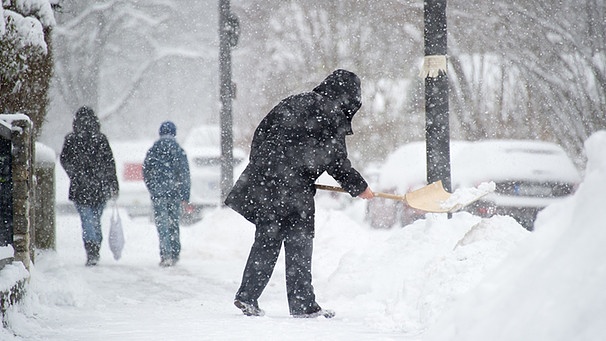 Ein Mann räumt in München Schnee vom Gehweg. | Bild: picture-alliance/dpa