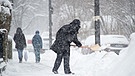 Ein Mann räumt in München Schnee vom Gehweg. | Bild: picture-alliance/dpa