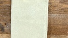 Roher Blätterteig auf 30x40 cm ausgerollt auf einer braunen Holzplatte; neben dem Teig liegt ein Lineal. Der Teig hat eine "einfache Tour" bekommen, wurde wie ein Blatt zu einem Drittel eingeschlagen. Das gegenüberliegende Ende wurde darüber gelegt, so dass drei Teigschichten entstehen. | Bild: Wir in Bayern