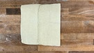 Roher Blätterteig auf 30x40 cm ausgerollt auf einer braunen Holzplatte; neben dem Teig liegt ein Lineal. Der Teig hat eine sogenannte "einfache Tour" bekommen - d.h. er wurde wie ein Blatt zu einem Drittel eingeschlagen. | Bild: Wir in Bayern