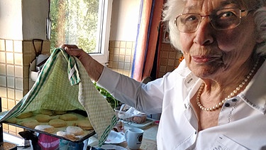 Maria Grötsch deckt die runden Teiglinge mit einem angewärmten Tuch ab | Bild: BR