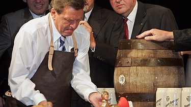 Bundeskanzler Gerhard Schröder sticht am Dienstag (09.08.2005) während einer Wahlkampfveranstaltung der SPD in Kösching bei Ingolstadt ein Fass Bier an.  | Bild: picture-alliance/dpa/Alexander Rüsche