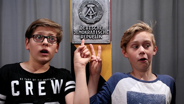 Zwei Jugendliche zeigen überrascht auf das Symbol der Deutschen Demokratischen Republik. | Bild: BR