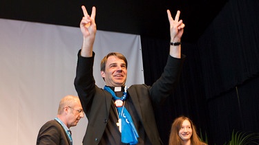Oster zeigt das Peace-Zeichen mit seinen Fingern | Bild: BR/ Markus Konvalin