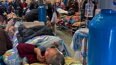 Mann auf Krankenhaus-Bett mit Sauerstoffgerät daneben. | Bild: AP