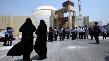 Iran, Buschehr: Zwei weibliche Sicherheitsbeamte stehen vor dem Atomkraftwerk Buschehr und beobachten Medienvertreter. | Bild: Abedin Taherkenareh/EPA/ dpa-Bildfunk 