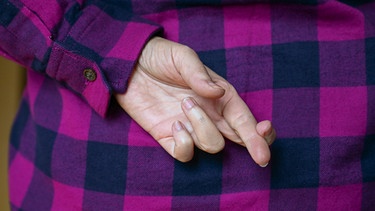 Gekreuzte Finger sind eine Handgeste, die beim Schwindeln verwendet wird, oder um ein Versprechen, einen Schwur aufzuheben. | Bild: picture alliance/dpa / Jens Kalaene