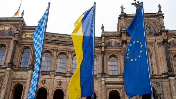 Bayern, München: Vor dem bayerischen Landtag wehen die Bayerische (l-r), die Ukrainische und eine Europa Flagge. Russische Truppen haben 24.02.2022 einen Angriff auf die Ukraine gestartet. | Bild: dpa-Bildfunk