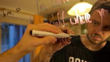 Erik schreibt auf einen Spiegel. | Bild: BR