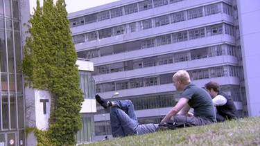 Studierende sitzen auf der Wiese vor Unigebäude | Bild: BR