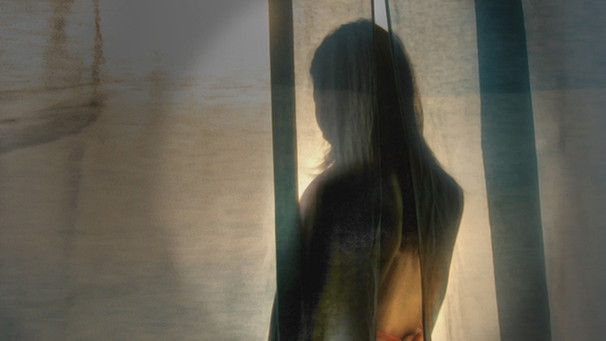 Junge Frau steht abgewendt hinter einem Vorhang; Foto: dpa | Bild: colourbox.com