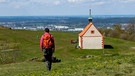 Ein einzelner Wanderer auf einem Tafelberg geht auf eine kleine Kapelle zu | Bild: picture alliance / Zoonar | Holger W. Spieker