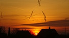 Die Sonne geht in faszinierenden Farben zwischen zwei Dächern in Erlangen-Häusling auf. | Bild: Uwe Wollenschlaeger, Erlangen, 18.12.2023